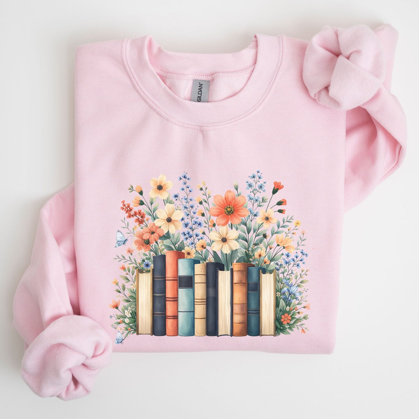 Pink sweatshirt with a design of books and flowers on a light background