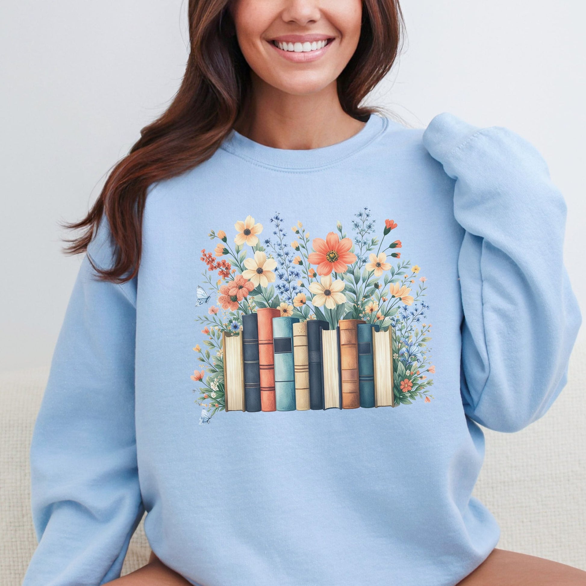 Person wearing a light blue sweatshirt with a floral and book design.