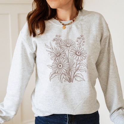 Person wearing a light gray sweatshirt with floral design on a plain background