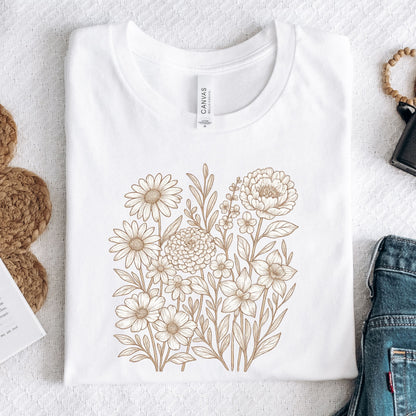 White t-shirt with floral design on a textured surface with accessories.