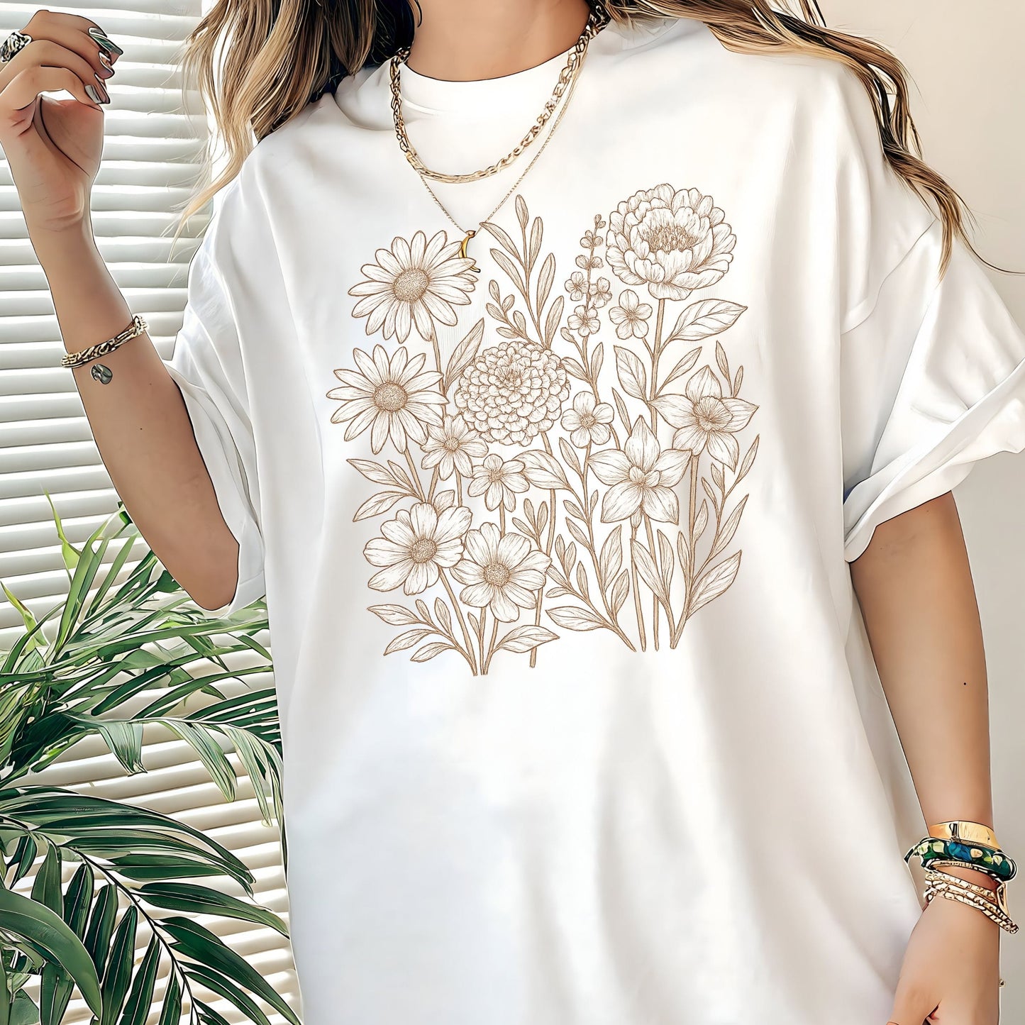 White t-shirt with floral design worn by a person, with a plant in the background