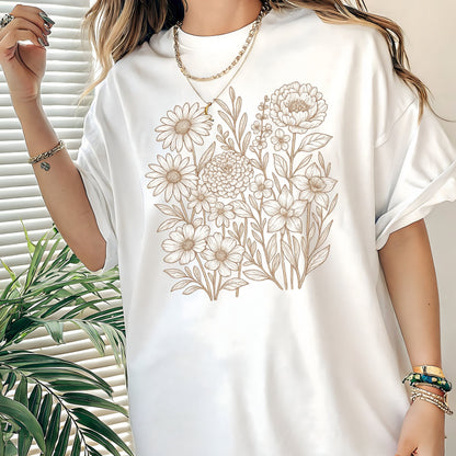 White t-shirt with floral design worn by a person, with a plant in the background