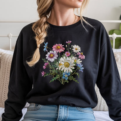 Person wearing a black long sleeve t-shirt with a floral design, sitting on a bed.