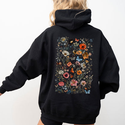 Person wearing a black hoodie with floral designs on the back against a white background