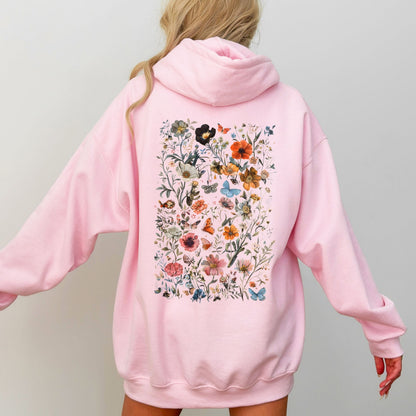 Pink hoodie with floral design on the back worn by a person against a plain background