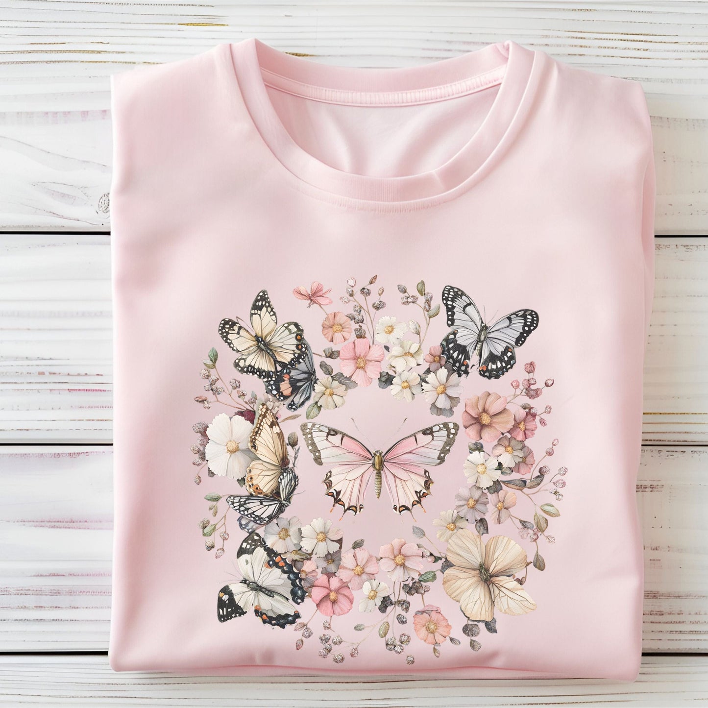 Pink t-shirt with butterfly and floral design on a wooden surface