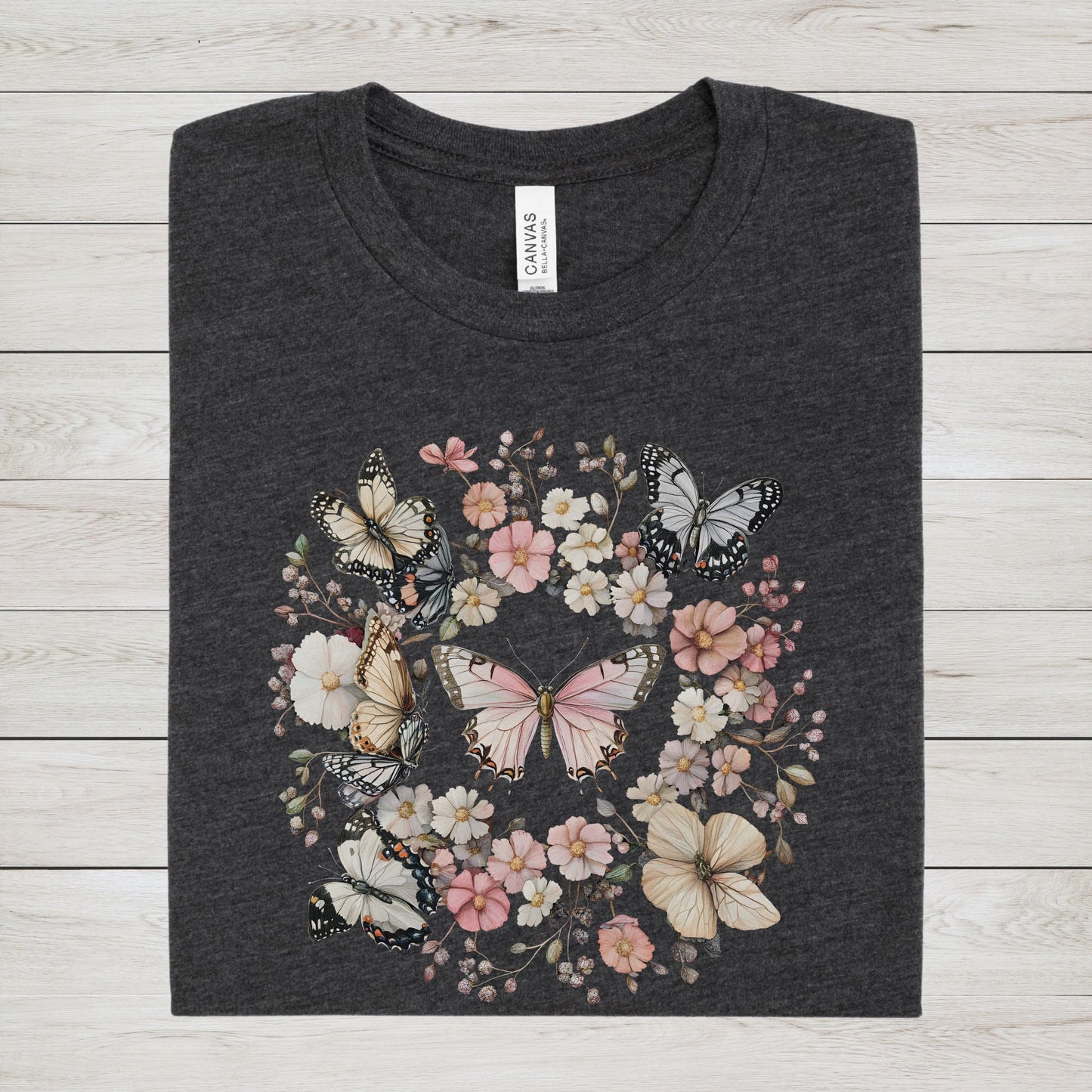 Dark gray t-shirt with butterfly and floral design on a wooden surface