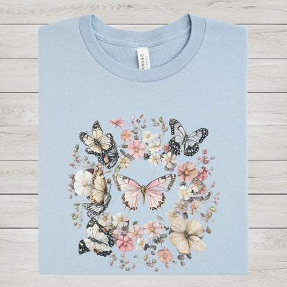 Light blue t-shirt with butterfly and floral design on a wooden surface