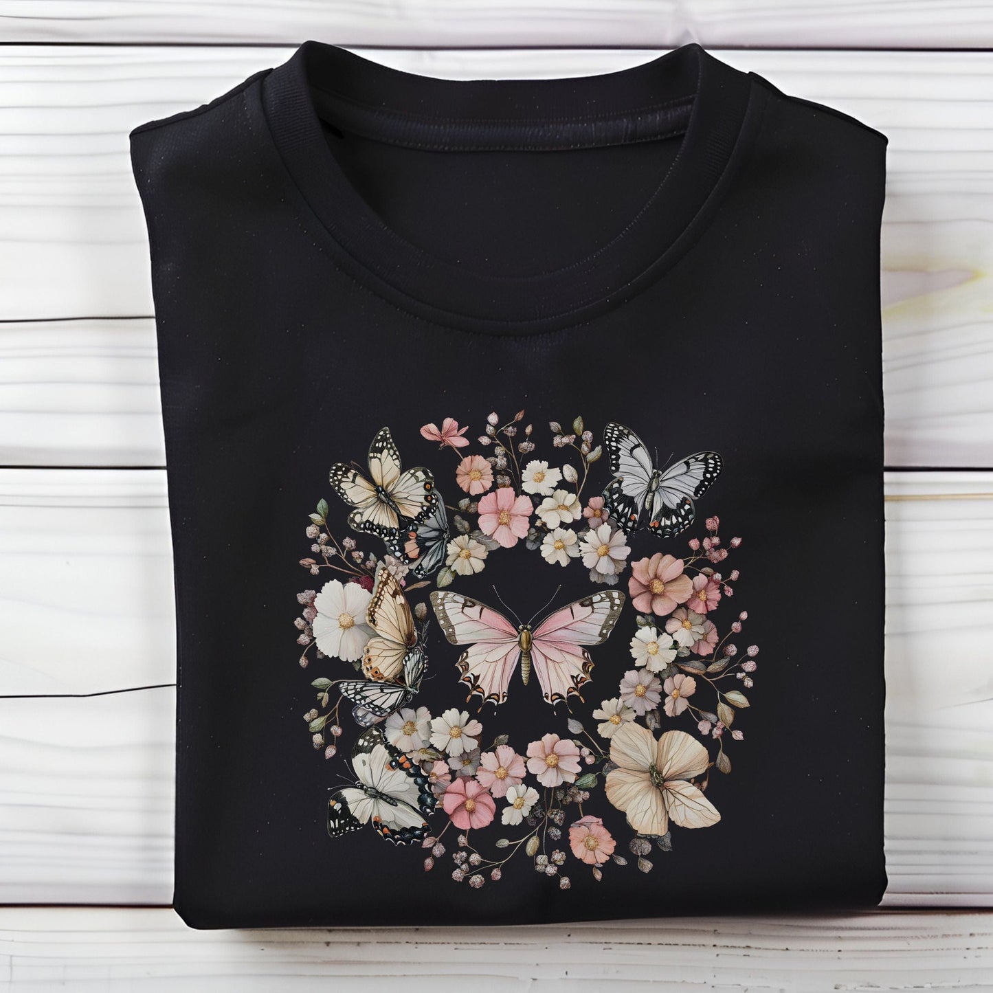 Black t-shirt with butterfly and floral design on a wooden surface