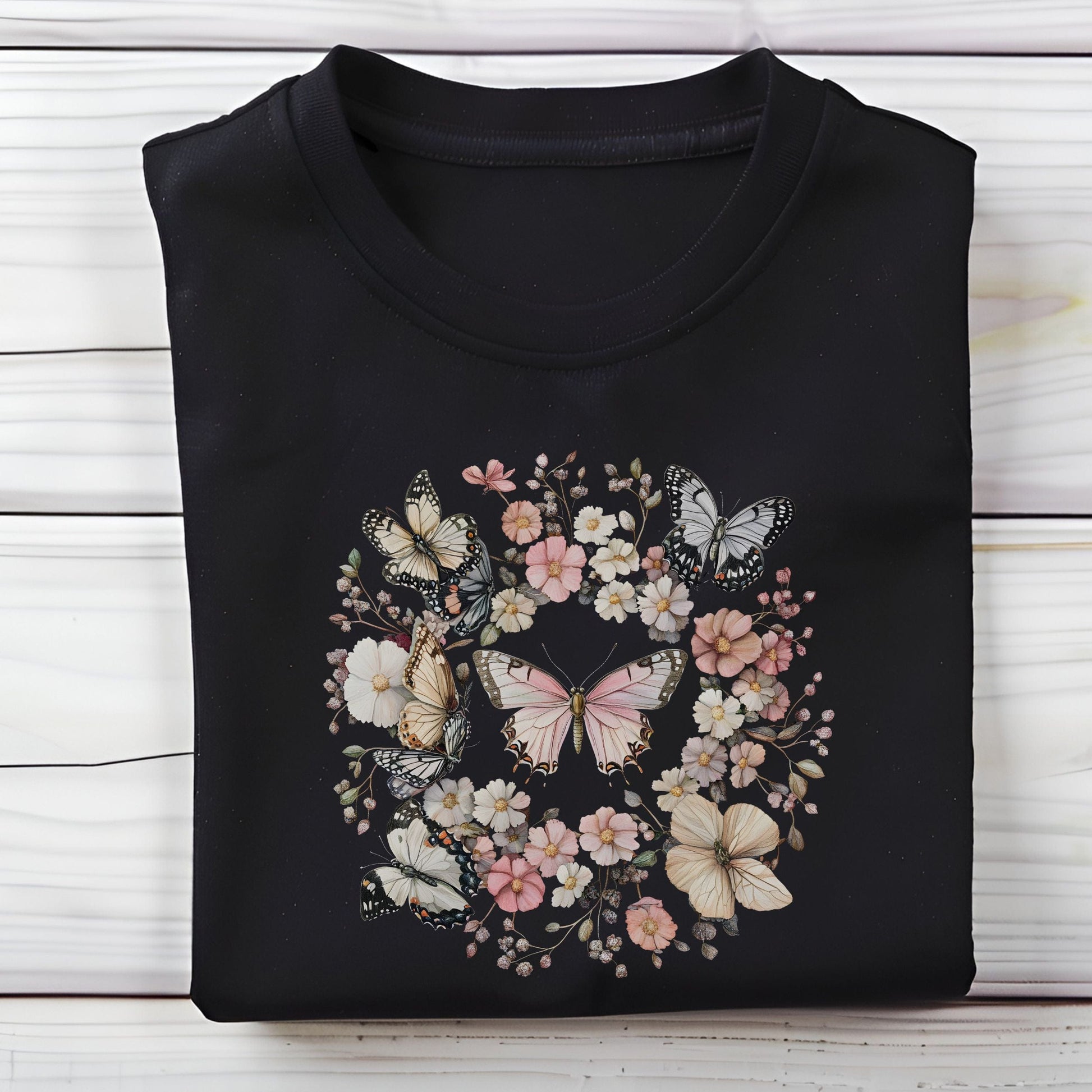 Black t-shirt with butterfly and floral design on a wooden surface