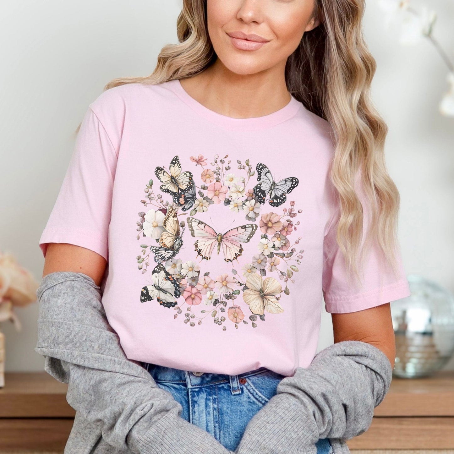 Woman wearing a pink t-shirt with butterfly design, sitting indoors.