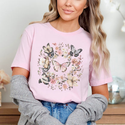 Woman wearing a pink t-shirt with butterfly design, sitting indoors.