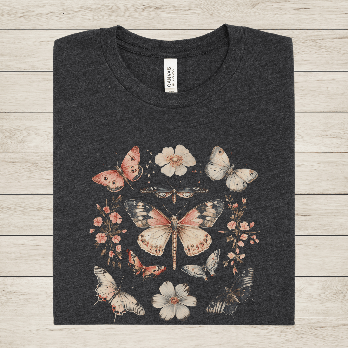Dark gray t-shirt with butterfly and floral design on a wooden surface