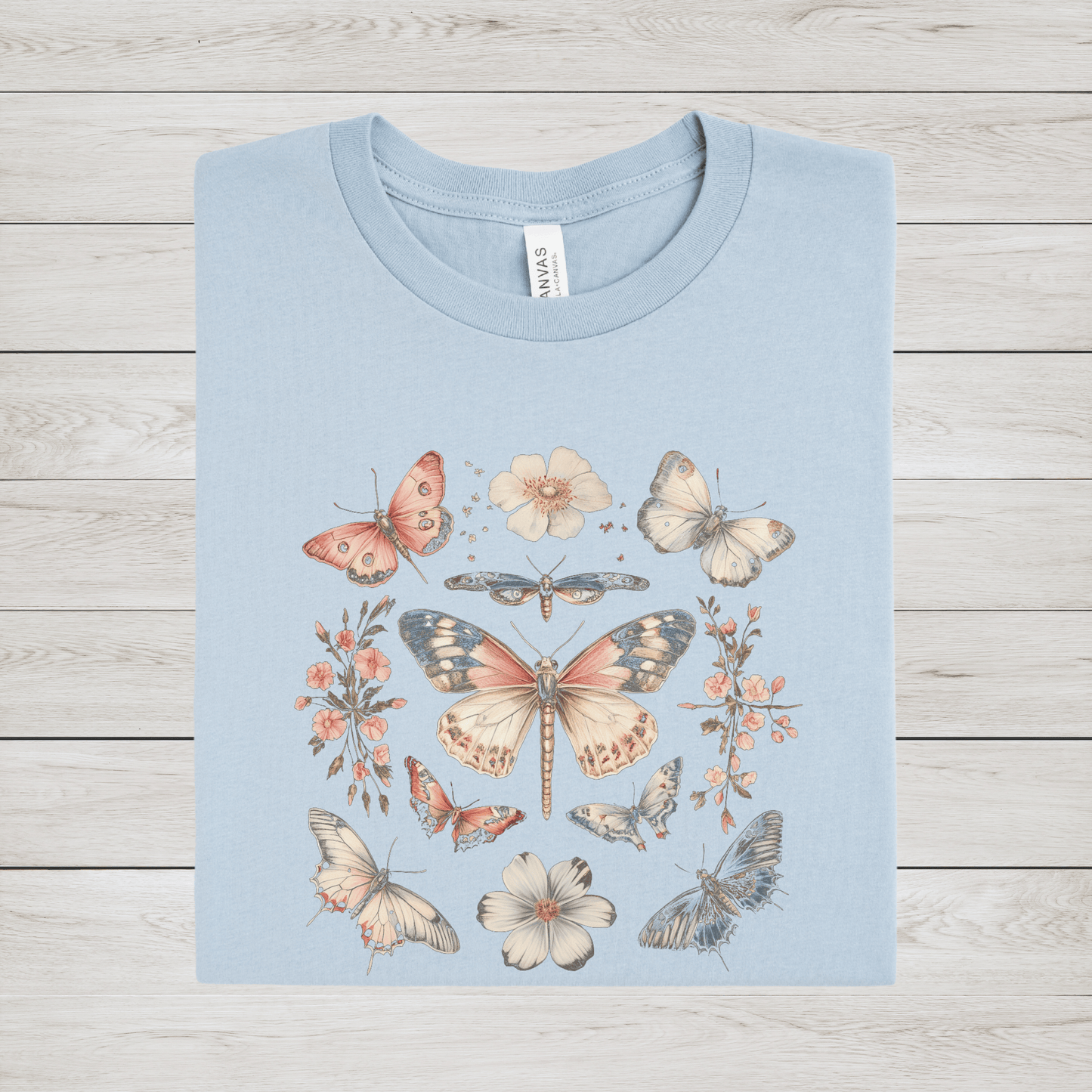 Flat lay of light blue t-shirt featuring vintage butterfly and floral design