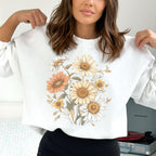 Person wearing a white sweatshirt with floral designs, holding it up to show the design.
