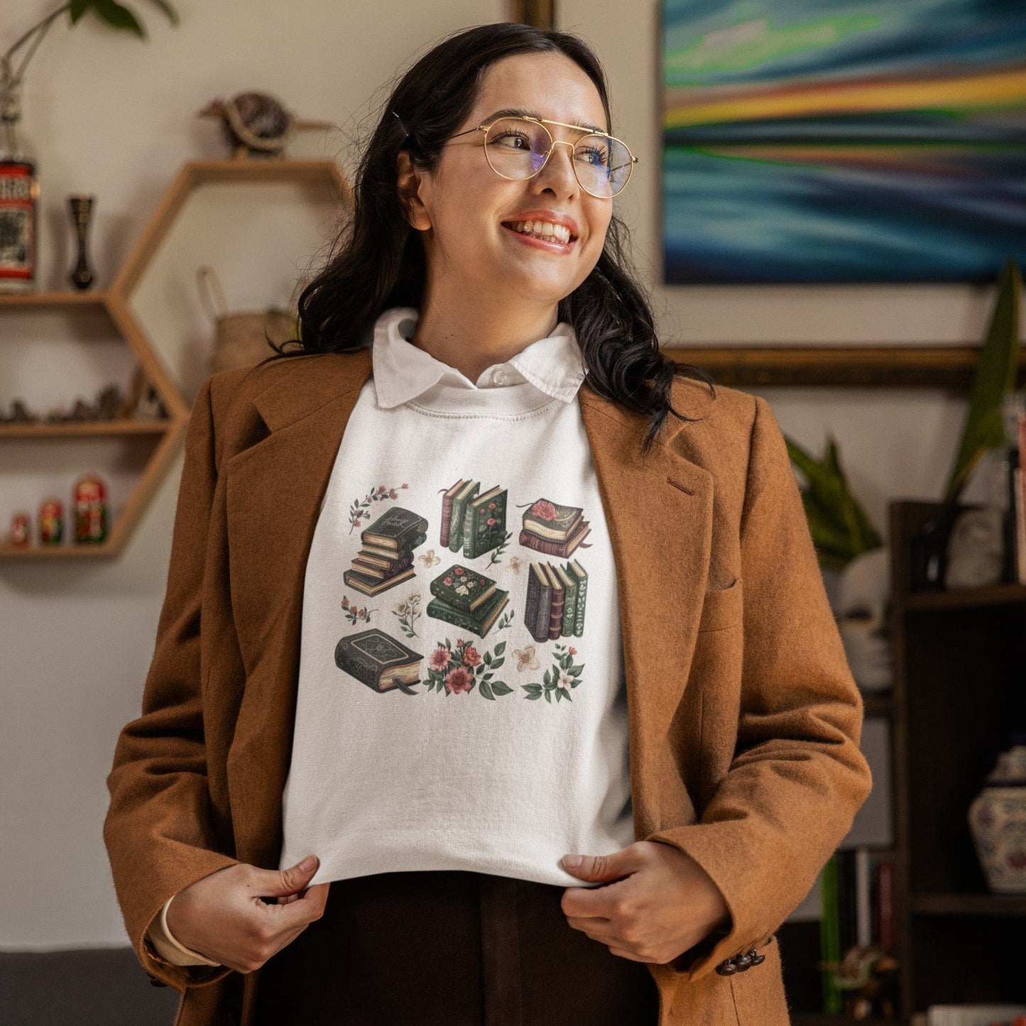 Woman wearing a brown coat over a white sweatshirt with book illustrations in a cozy room.