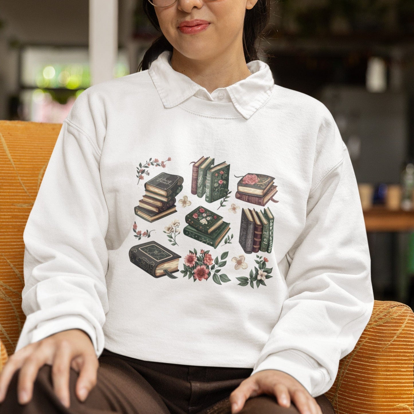 Person wearing a white sweatshirt with book design sitting on an orange chair.