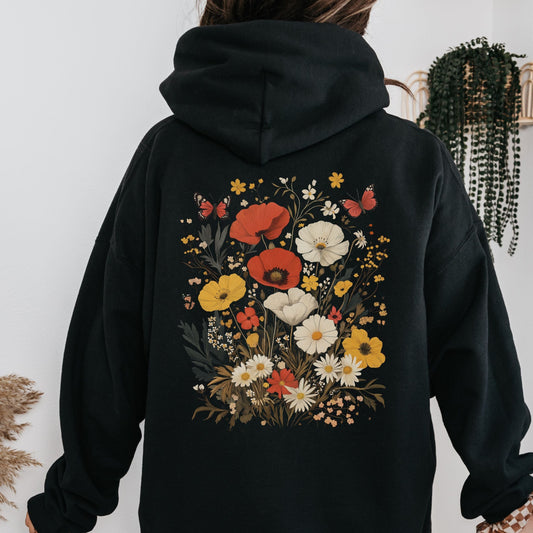 Black hoodie with floral design on the back against a white wall.