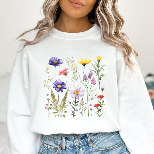 White sweatshirt with floral design worn by a person, against a neutral background