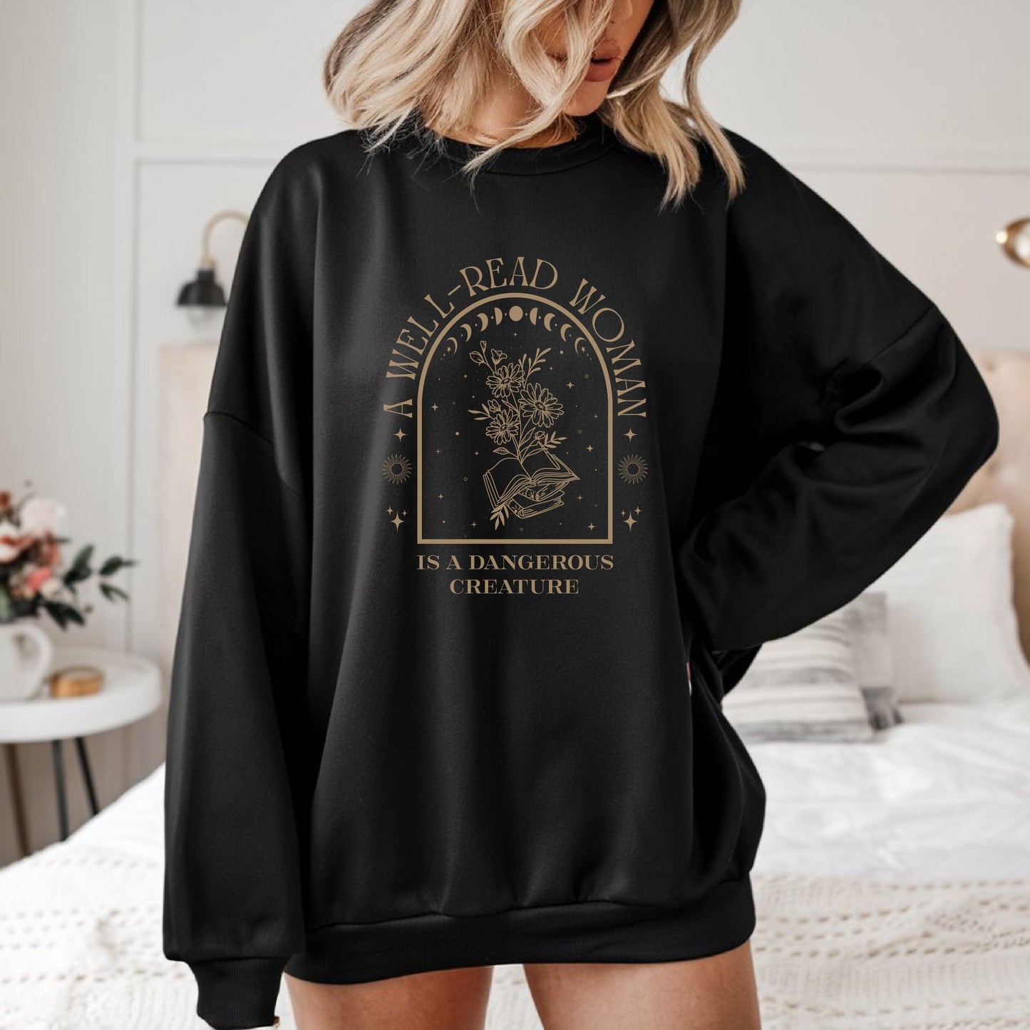 Person wearing a black sweatshirt with 'A well-read woman is a dangerous creature' text and graphic.