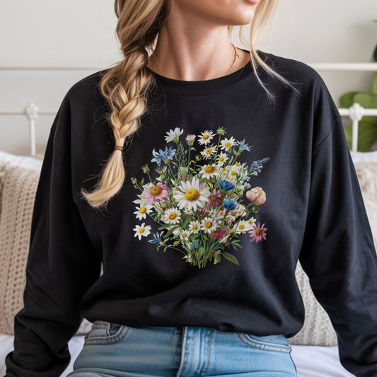 Person wearing a black long sleeve t-shirt with a floral design, sitting on a bed.