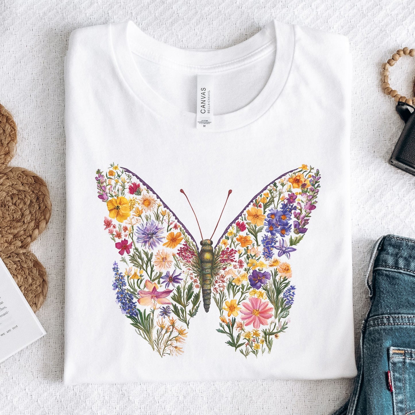 White t-shirt with a colorful butterfly design on a textured surface.