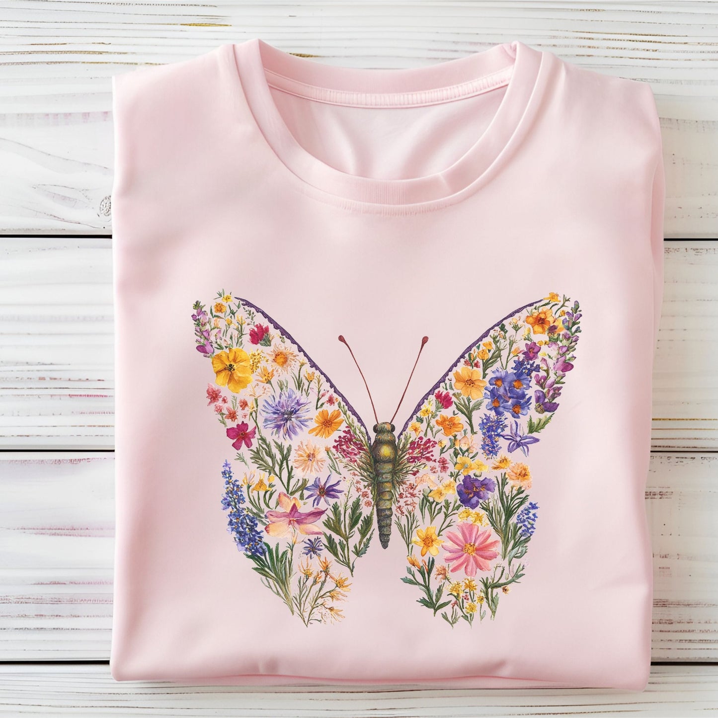 Pink t-shirt with a butterfly and floral design on a wooden surface