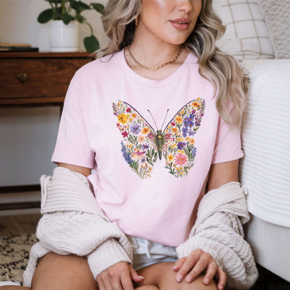 Woman wearing a pink t-shirt with a colorful butterfly design, sitting on a couch.