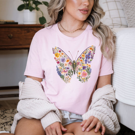 Woman wearing a pink t-shirt with a colorful butterfly design, sitting on a couch.