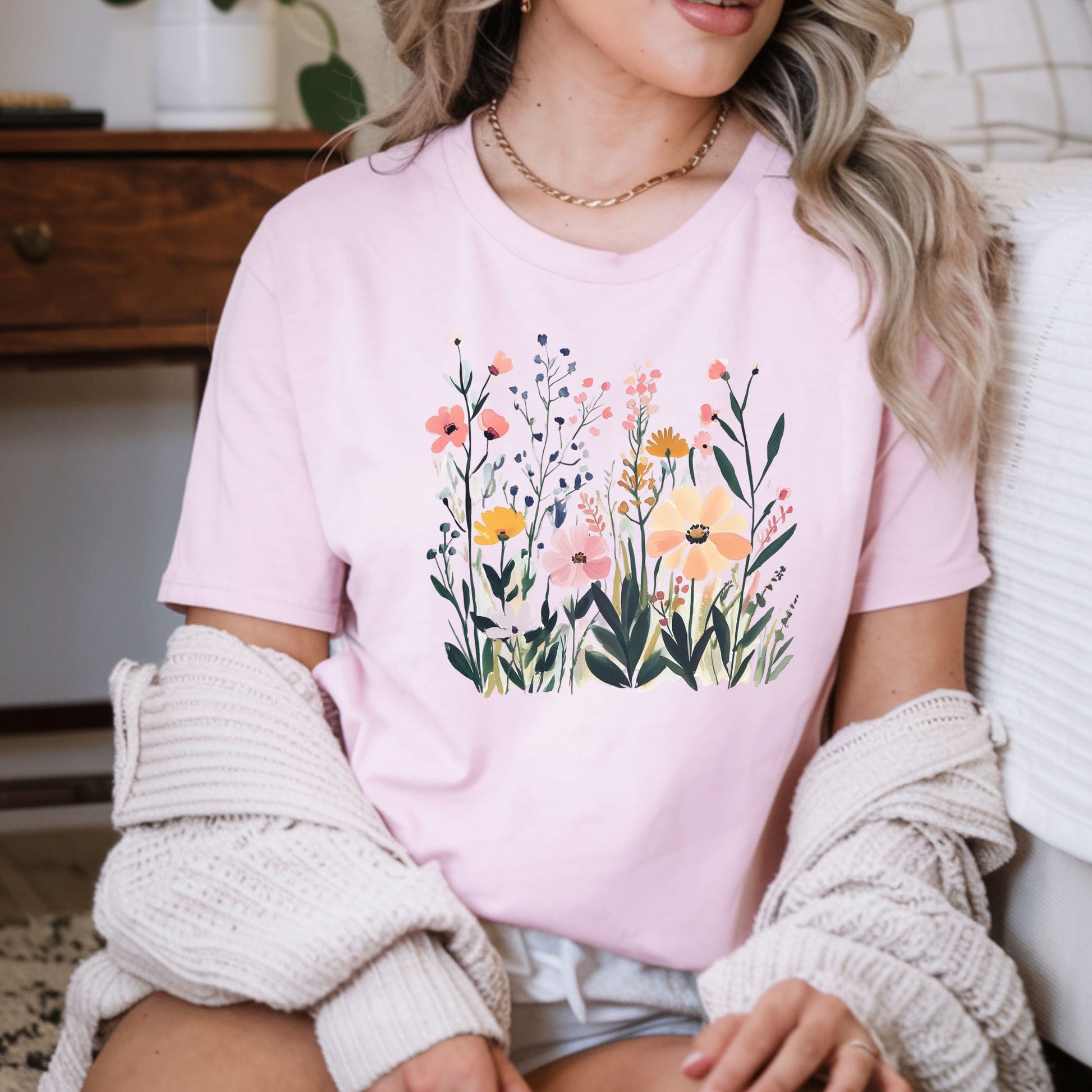 Person wearing a pink t-shirt with floral design sitting on a couch.