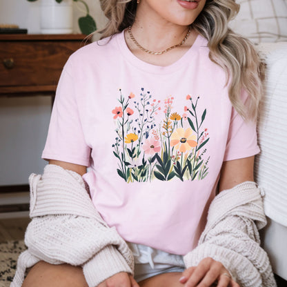 Person wearing a pink t-shirt with floral design sitting on a couch.