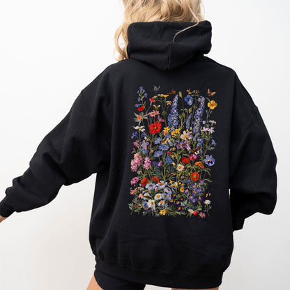 Person wearing a black hoodie with floral designs on the back against a white background