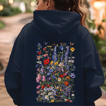 Person wearing a navy hoodie with a colorful floral design on the back, standing outdoors.