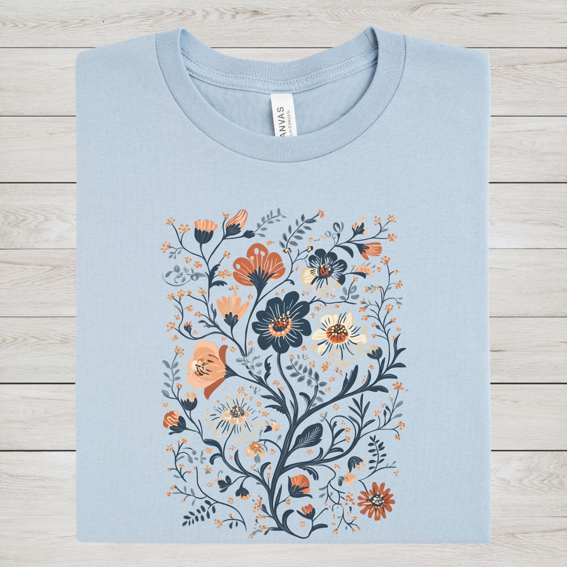 Light blue t-shirt with floral design on a wooden surface