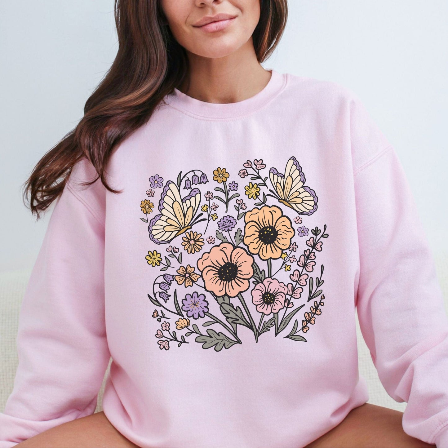 Person wearing a pink sweatshirt with floral and butterfly design