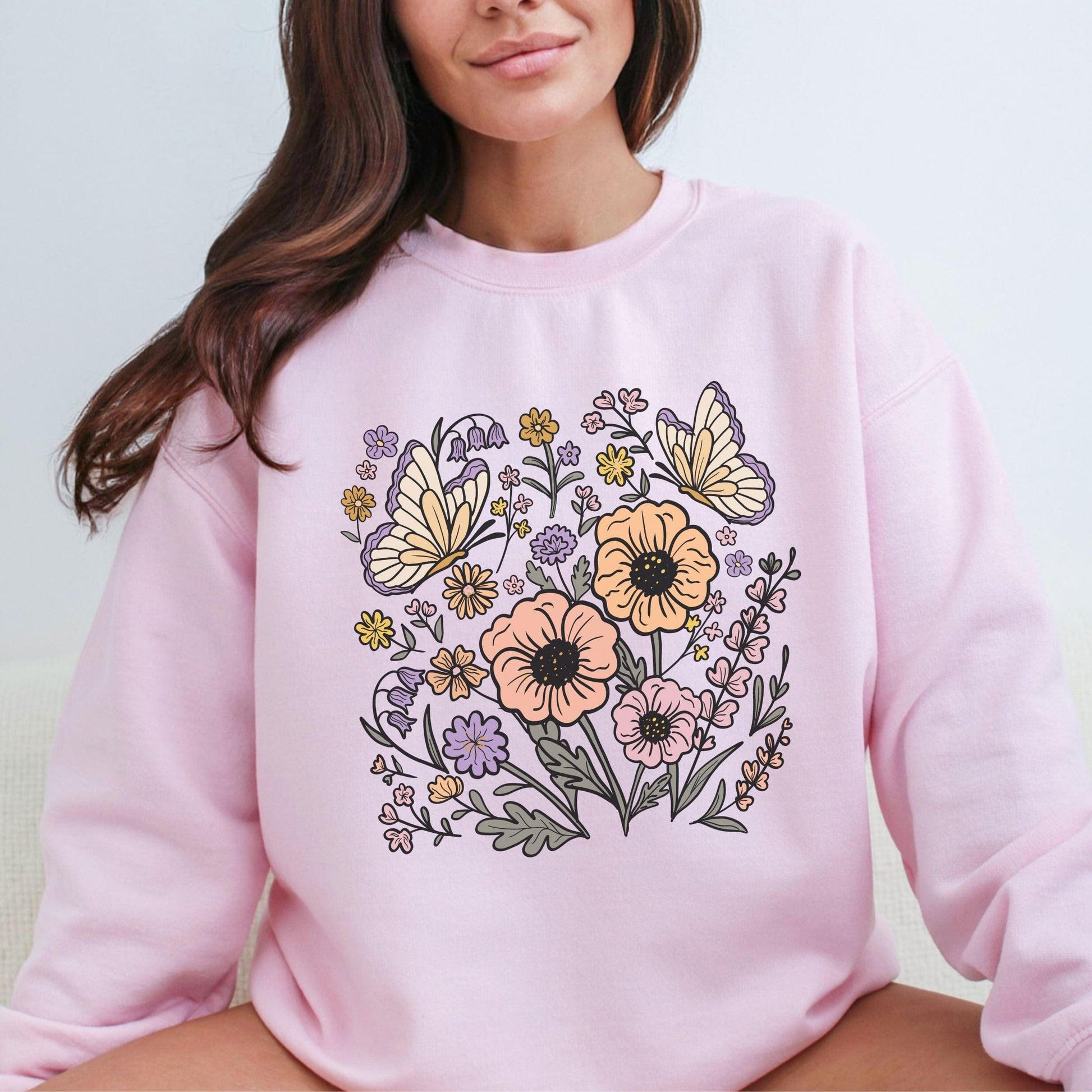 Person wearing a pink sweatshirt with floral and butterfly design