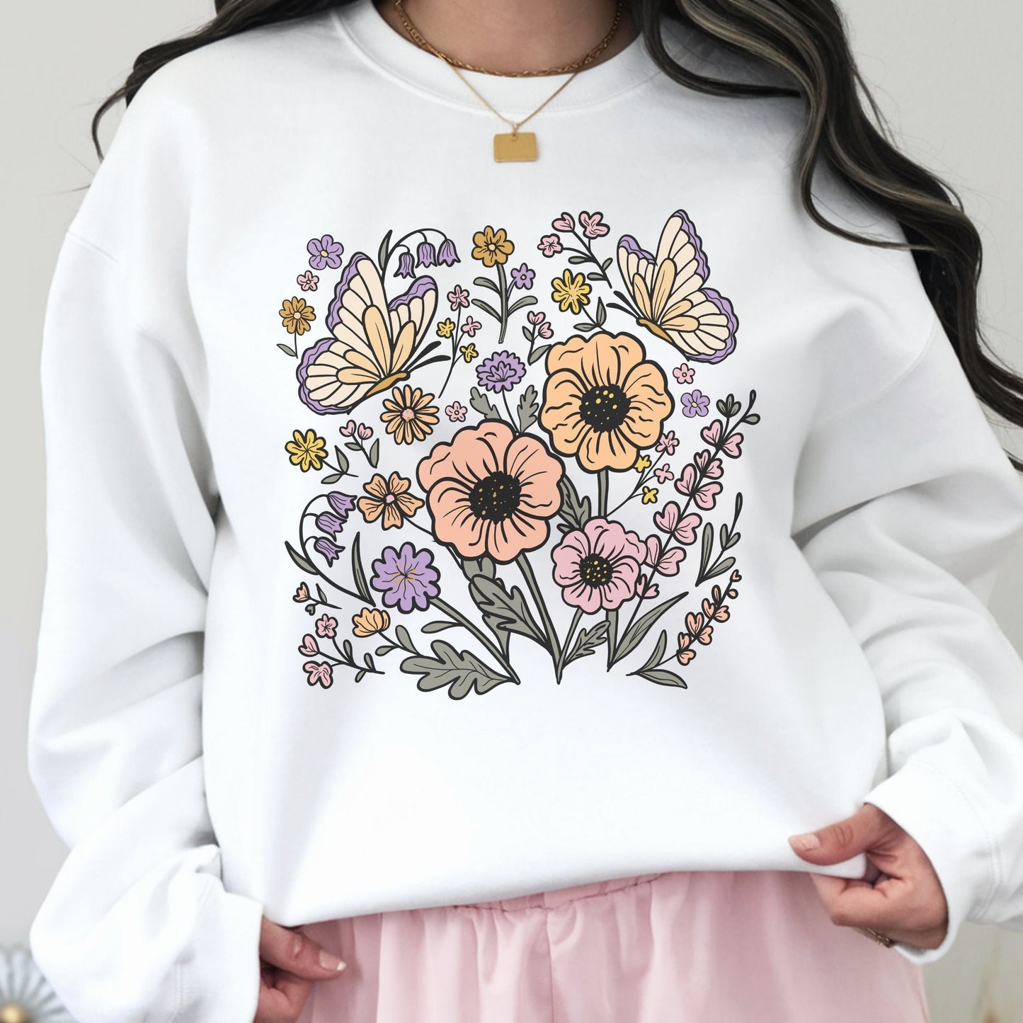 White sweatshirt with floral and butterfly design held by a person