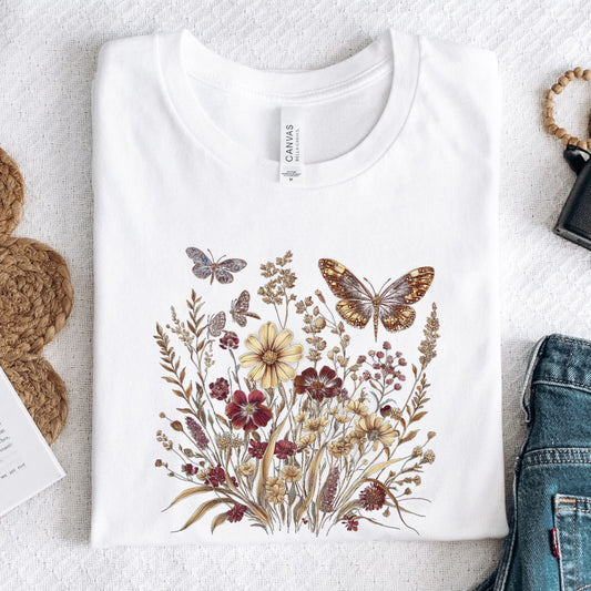White t-shirt with butterfly and floral design on a textured surface