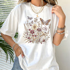 Person wearing a white t-shirt with floral and butterfly design, standing indoors.