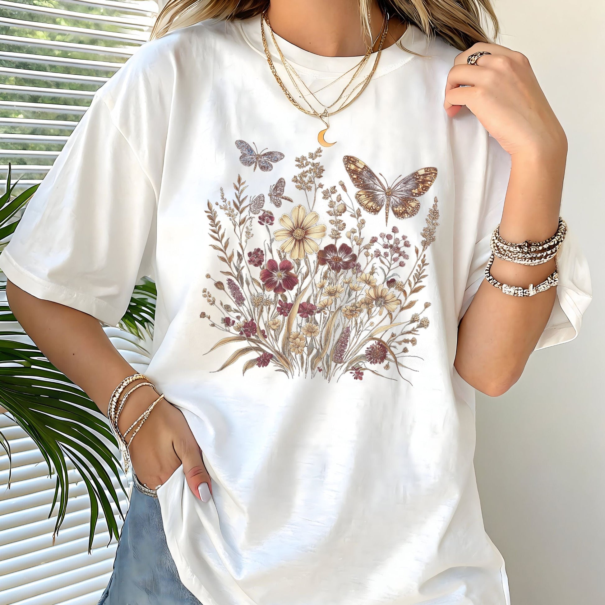 Person wearing a white t-shirt with floral and butterfly design, standing indoors.