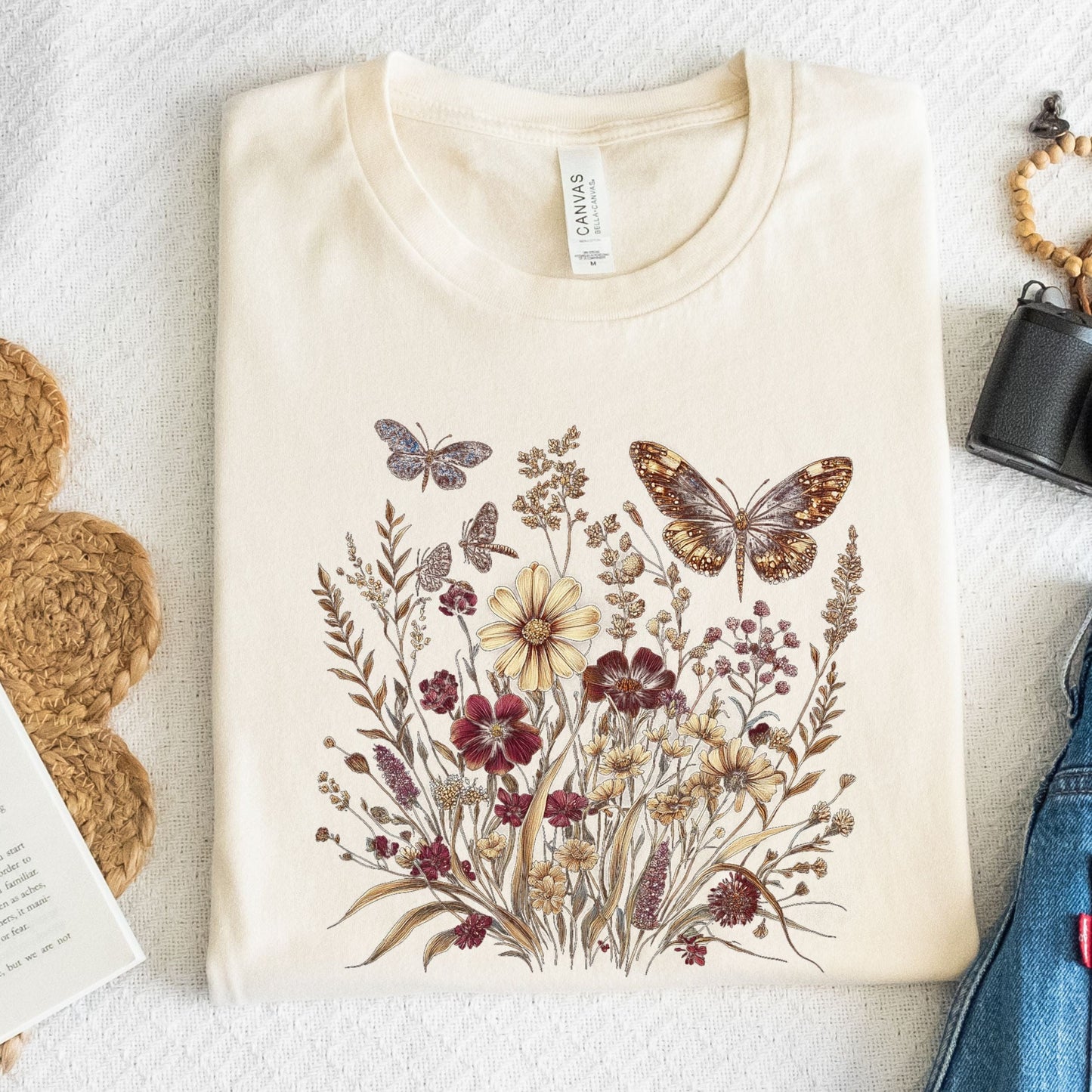 Beige t-shirt with butterfly and floral design on a textured surface