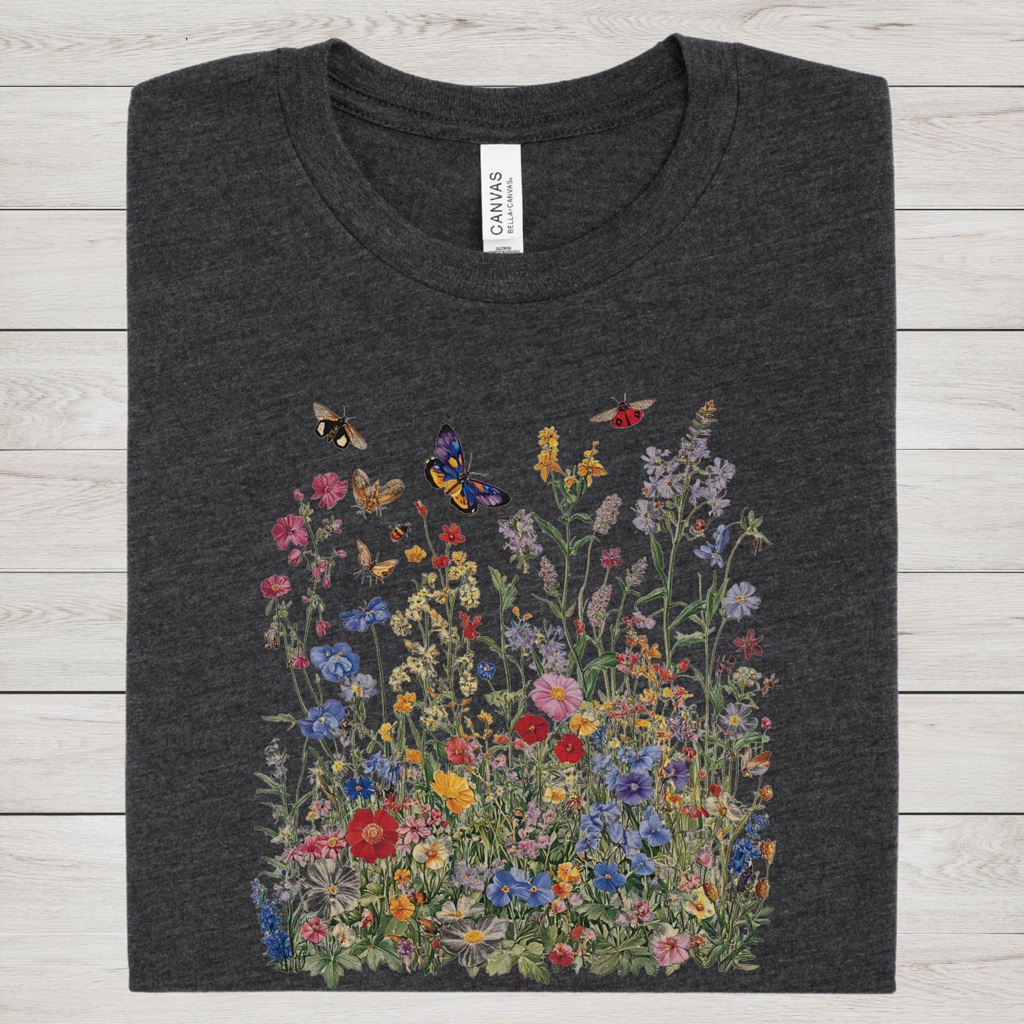 Flat lay of dark grey heather t-shirt featuring colorful wildflower meadow with butterflies