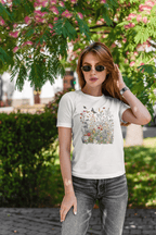 Woman wearing a white t-shirt with a colorful graphic design outdoors.