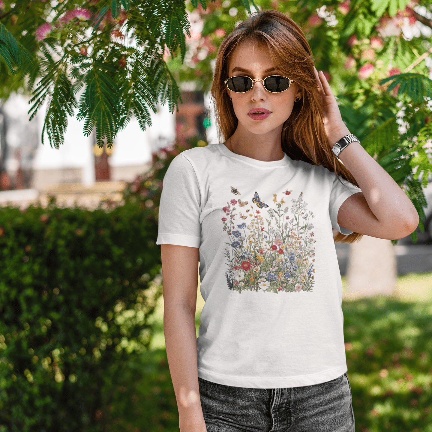 Woman wearing a white t-shirt with a colorful graphic design outdoors.