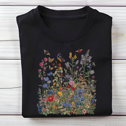 Flat lay of black t-shirt featuring colorful wildflower meadow with butterflies