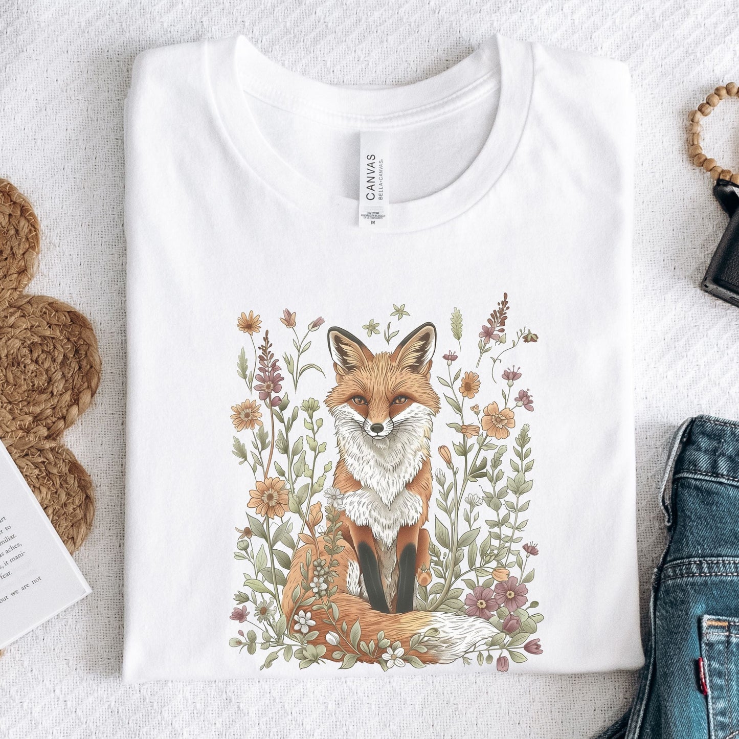 Flat lay of white t-shirt featuring woodland fox surrounded by flowers