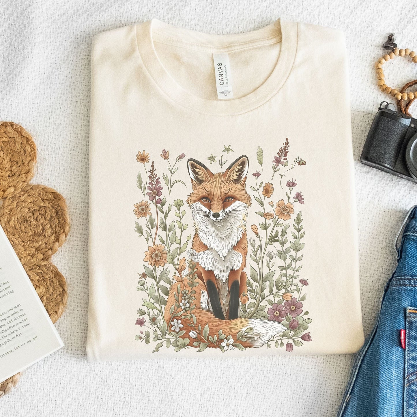 Flat lay of beige t-shirt featuring woodland fox surrounded by flowers
